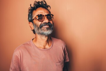 Fototapeta premium Portrait of a joyful indian man in his 40s wearing a trendy sunglasses isolated on pastel brown background