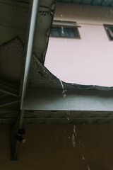 Raindrops falling from the edge of a roof tile, captured mid-drop