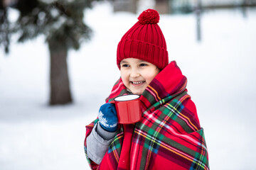 Happy child girl holding mug of hot cocoa, chocolate or tea. Children activity in winter day. Holiday vacation concept.