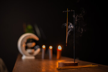 incense stick smokes on a wooden stand on a dark background. Aromatherapy, Smoke while burning...