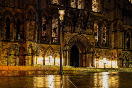 Tranquil, night scene of a vintage wrought iron street lantern seen lit against a majestic cathedral in York, England. The street is deserted of people, being a cold and wet November night. - Powered by Adobe