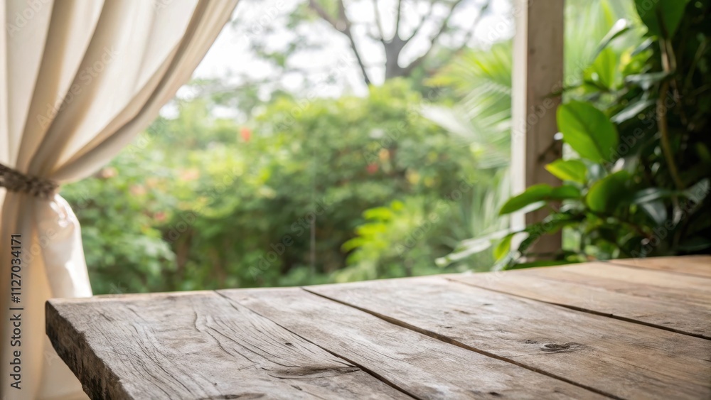Poster close-up of a weathered wooden table with a blurred background of lush greenery and a white curtain