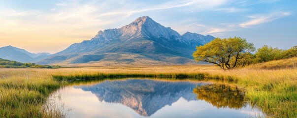 Fototapeta premium A peaceful reflection of a towering mountain peak is mirrored in the calm waters of a tranquil pond, creating a serene and breathtaking scene.