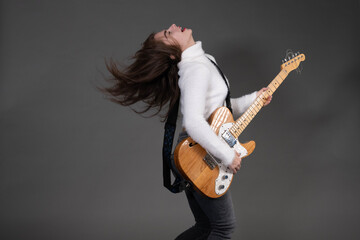 Cool young woman playing electric guitar on grey background