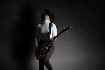 Cool young woman playing electric guitar on grey background