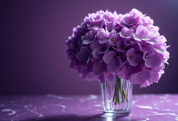 A bouquet of vibrant purple hydrangeas sits in a clear glass vase on a purple marble surface.