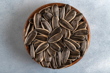 Black sunflower seeds in a bowl on light background