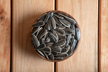 Black sunflower seeds in a bowl on wooden background