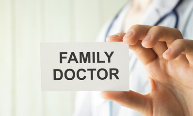 A doctor in medical clothing puts a card with the text FAMILY DOCTOR. Medical concept.