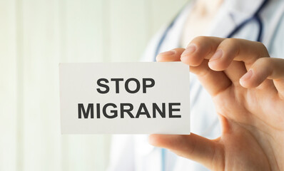 Doctor holding a card with Stop Migraine, medical concept
