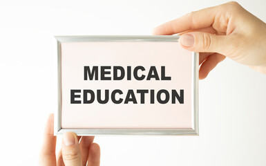 Hands holding clipboard with text medical education on a sheet of paper on a white background
