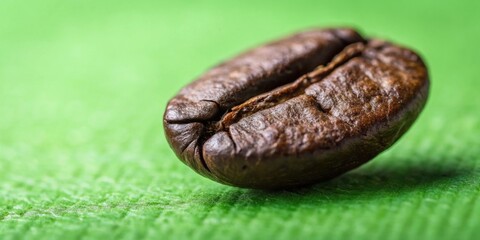 Obraz premium A Single Roasted Coffee Bean in Close-Up, Revealing its Rich Brown Hue and Intricate Surface Texture Against a Soft Green Background