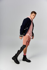 A young man in stylish attire poses confidently in a studio, highlighting his prosthetic leg.