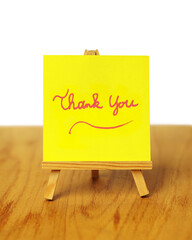 Handwritten yellow thank you note on a miniature easel.