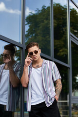 A young man stands confidently outside a modern building.