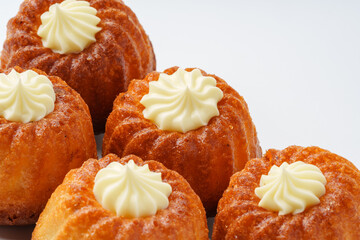 Mini bundt cakes with cream frosting on top displayed against a white background