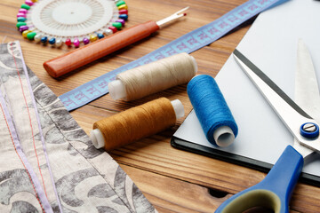 Colorful sewing supplies arranged around a blank clipboard on a wooden table