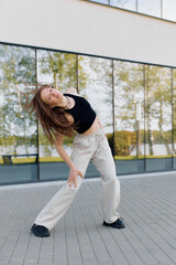 A dancer performs an expressive pose outside a modern building