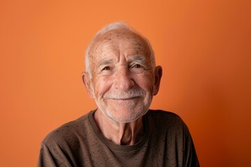 Obraz premium Portrait of a smiling caucasian man in his 80s donning a trendy cropped top on soft orange background