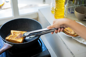 a woman's hands are toasting a sandwich in a frying pan