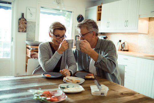 Happy senior couple having breakfast and coffee together at home