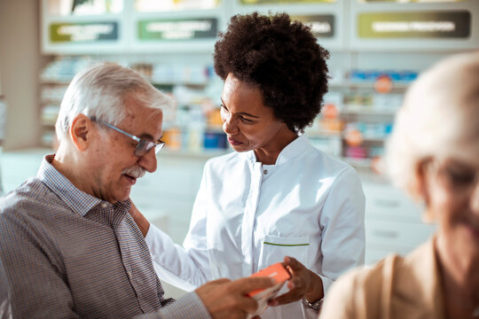Pharmacist assisting senior couple with medication choice in pharmacy