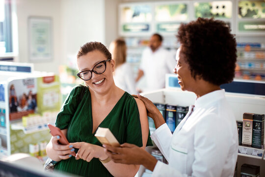 Female pharmacist helping pregnant woman in drug store