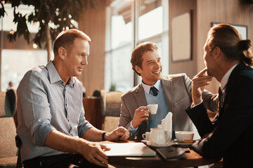 Businessmen enjoying a relaxed meeting with coffee in a sunlit cafe