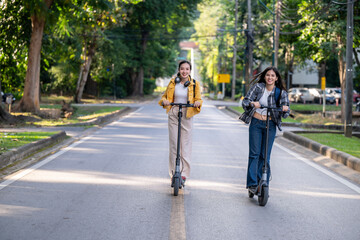 Two women riding scooters down a street