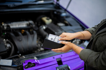 Young Indonesian woman wearing hijab spends money to pay for car repairs, automotive industry concept.