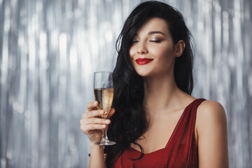 Beautiful brunette woman in a red dress holding a champagne glass with a serene smile, set against...