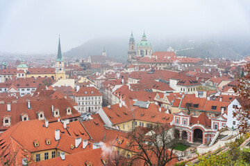 Obraz premium Panoramic view of the city of Prague with its old buildings and red roofs on a day of thick fog.