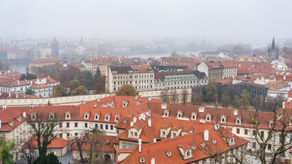 Obraz premium Panoramic view of the city of Prague with its old buildings and red roofs on a day of thick fog.