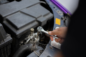 Indonesian male mechanic doing repairs on car engine, automotive industry concept.