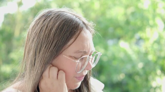 mature woman hears ringing in ear, health problems, Tinnitus symptom, gazing thoughtfully, psychological challenges, reflecting on health concerns