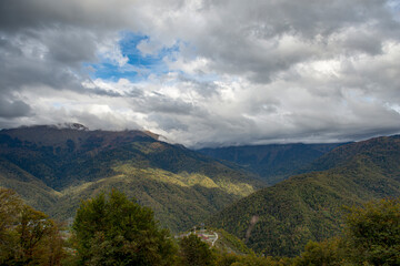 Cloudy evening at a picturesque mountain resort in autumn, heavy thunderclouds. Mountain peaks are shrouded in dark clouds. Early autumn, picturesque mountain ranges