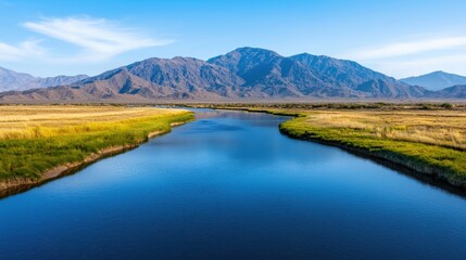Obraz premium Clean river flowing through desert terrain with mountains in background
