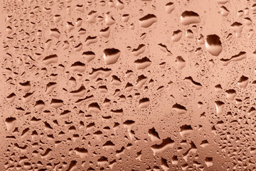 Drops on glass in sunset glow close up. Perfect Mocha brown background for your design and inspiration. Selective focus, defocus. Demonstrating color of 2025 year