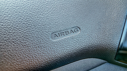 Close-up of a textured car dashboard featuring an airbag label, symbolizing automotive safety and...