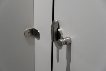 A pair of sleek stainless steel locks are fastened to a white cabinet door, highlighting the modern design elements of the interior space