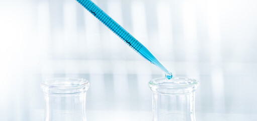 Doctor or scientist using pipette to drop a sample to test tube in medical research lab or science laboratory