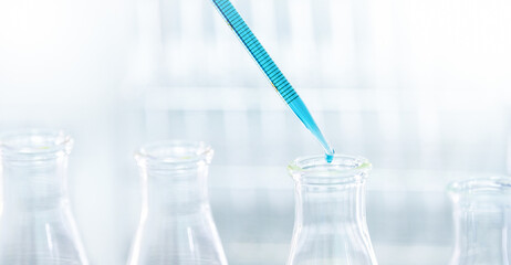 Doctor or scientist using pipette to drop a sample to test tube in medical research lab or science laboratory