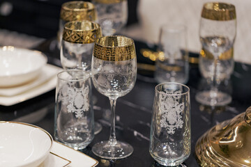 A beautifully arranged table features intricate glassware with gold accents alongside high quality dishware, ready for a memorable dining experience. Serving glassware and dishware for new year party