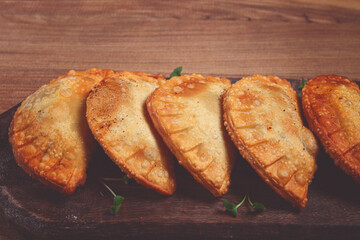 fried chebureks, deep-fried, mini, on a chopping board, wooden table, close-up, no people,