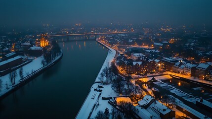 Fototapeta premium Aerial view of a snow-covered city at twilight, with a river winding through it, illuminated by warm lights.