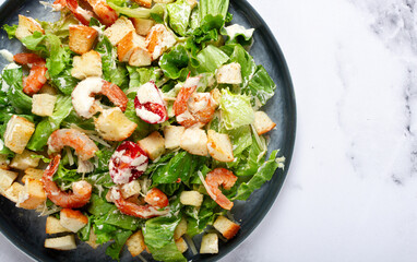 Caesar salad, with shrimp, on a marble background, top view, no people,
