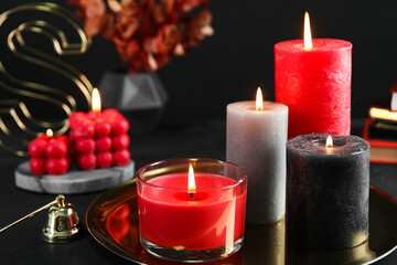 Beautiful burning candles and decor on black table, closeup