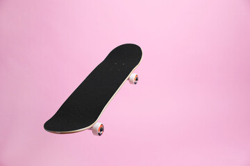 One skateboard on pink background, space for text. Sports equipment