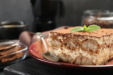 Delicious tiramisu with mint on table, closeup
