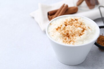 Delicious rice pudding with cinnamon on light table, closeup. Space for text